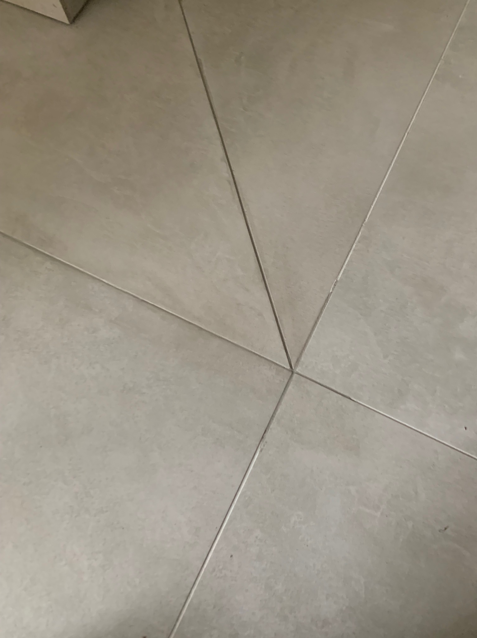 Beżowe płytki podłogowe ułożone z widocznymi fugami, neutralne oświetlenie.