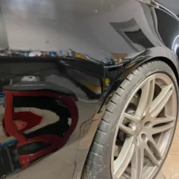 Błyszczący, czarny błotnik samochodu Audi po polerowaniu, widoczne odbicia otoczenia, felga aluminiowa z logo Audi, narzędzia polerskie w tle.