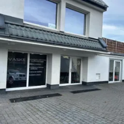 Fasada budynku firmy VASKE detailing&painting z witryną przedstawiającą ofertę: punktowe lakierowanie samochodów, woski i powłoki, renowacja tapicerki skórzanej, detailing wnętrza i korekta lakieru...