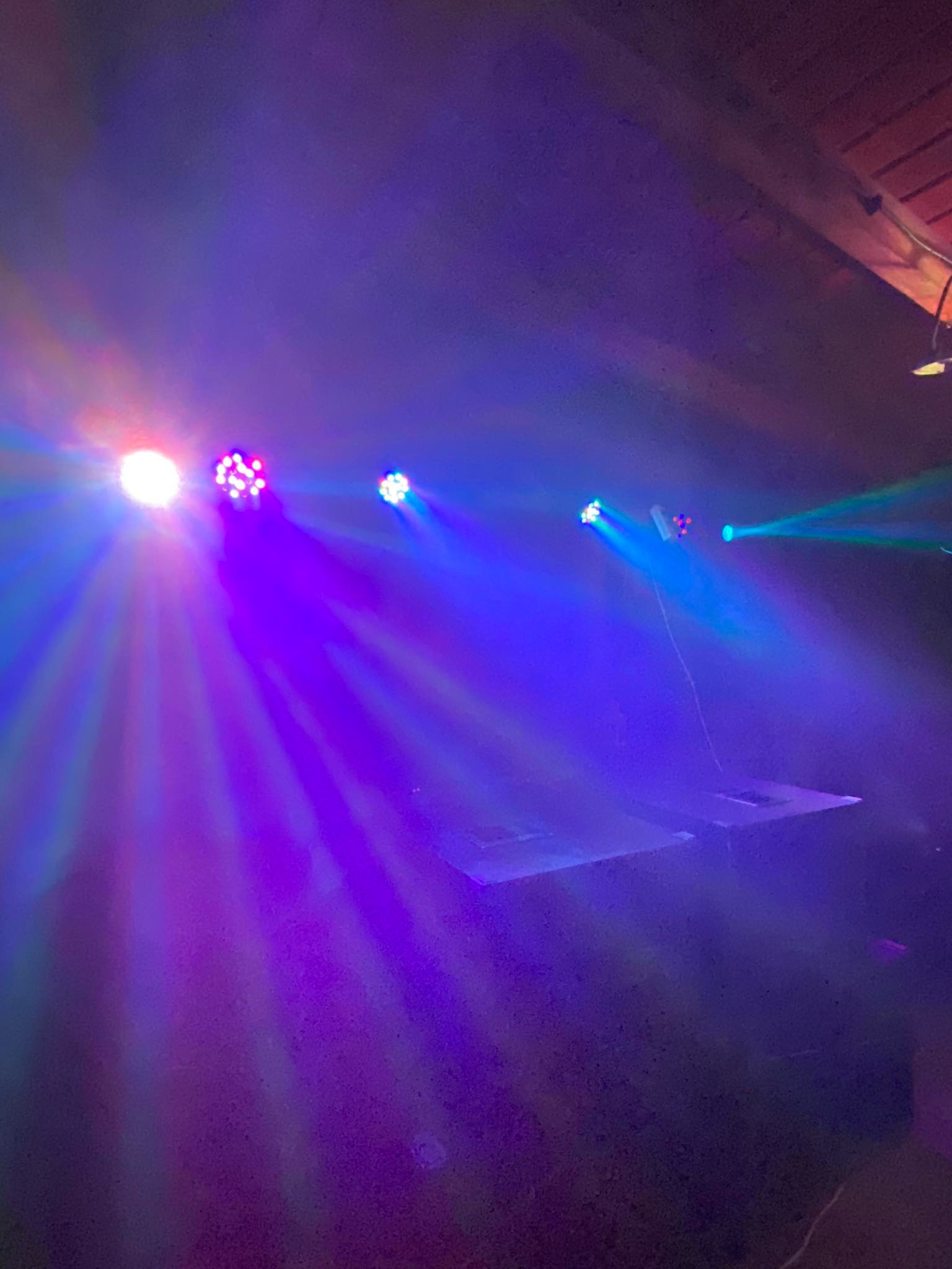 Efekty świetlne w fioletowych i niebieskich barwach, prawdopodobnie podczas realizacji nagłośnienia i oświetlenia imprezy w Niepruszewie, widoczne dwie platformy sceniczne.
