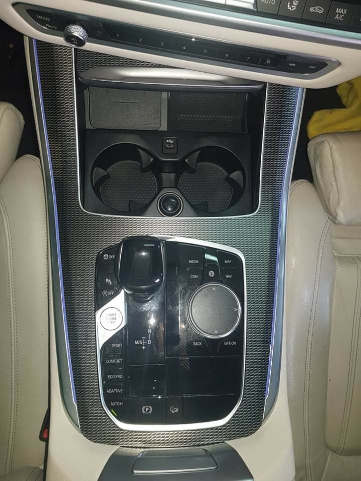 Wnętrze luksusowego samochodu z widoczną konsolą środkową po czyszczeniu, z detalami takimi jak podświetlane krawędzie i skórzane siedzenia w kolorze kremowym, sugerujące dbałość o detale i wysoką...