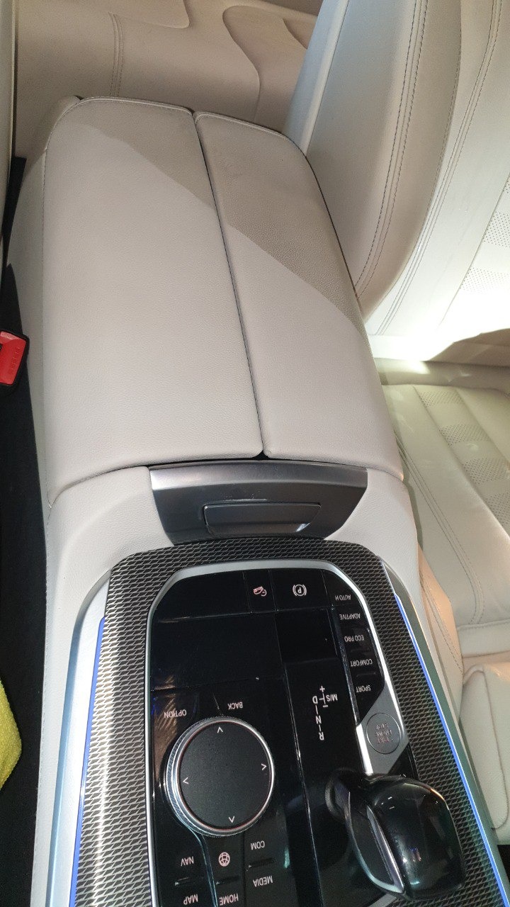 Jasna, skórzana tapicerka konsoli środkowej samochodu BMW, widok z góry, detale przycisków i panelu sterowania.