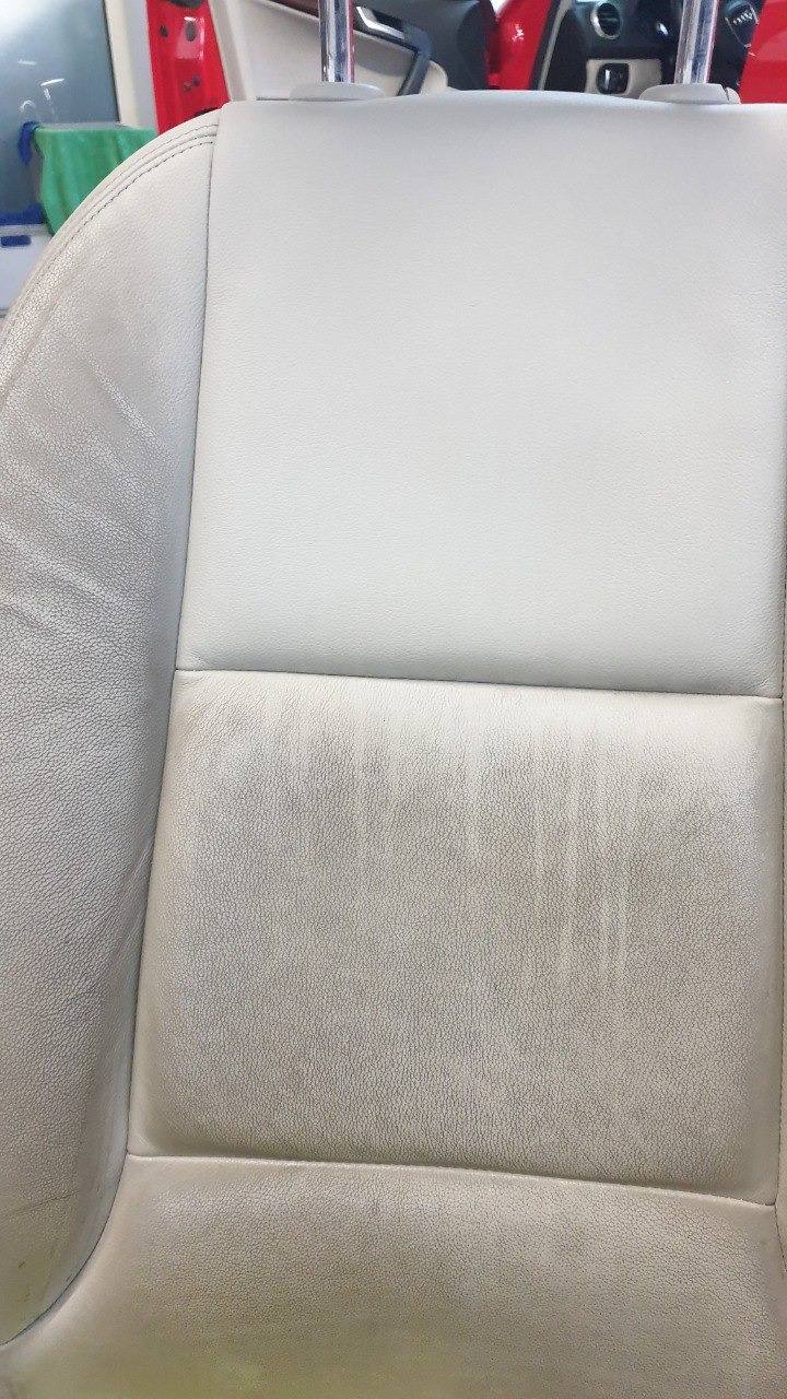 Jasna, skórzana tapicerka fotela samochodowego z widocznymi smugami po czyszczeniu, ukazująca efekt prania.