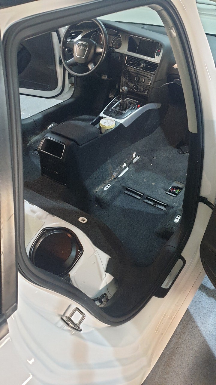Wnętrze samochodu Audi A4 po demontażu elementów podłogi, przygotowane do czyszczenia tapicerki, widoczne ślady zabrudzeń i resztki pożywienia.