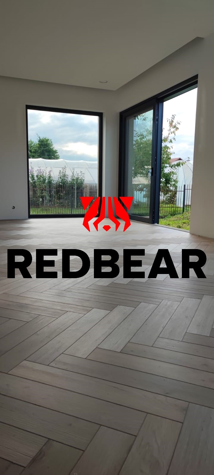Wnętrze z dużymi oknami i podłogą ułożoną w jodełkę, z naniesionym logo firmy Redbear.