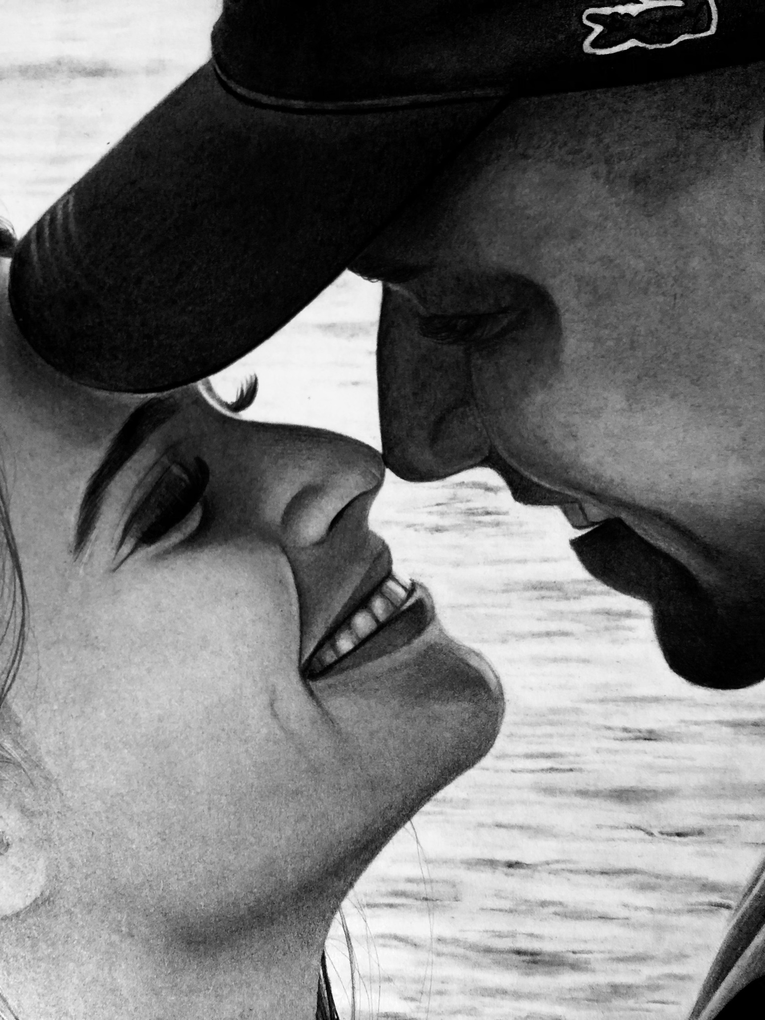 Czarno-biały rysunek ołówkiem przedstawiający zbliżenie twarzy uśmiechniętej kobiety i mężczyzny w czapce z daszkiem, na tle delikatnie zarysowanej wodnej powierzchni.