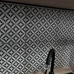 Ściana nad blatem kuchennym wyłożona białymi płytkami z czarnym geometrycznym wzorem kwiatowym, widoczny czarny kran z elementami chromowanymi.