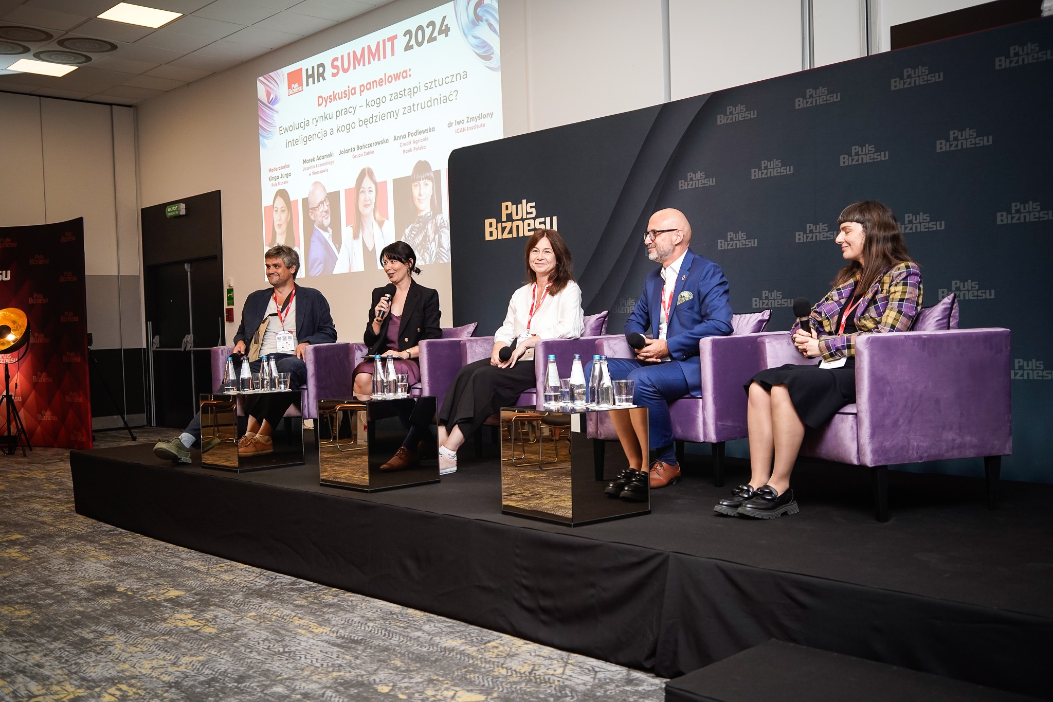 Panel dyskusyjny HR Summit 2024 w Łodzi, z udziałem ekspertów i logo Puls Biznesu w tle, moderowany przez Kingę Jurgę.