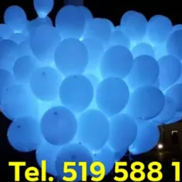 Duża wiązka białych balonów z niebieskim podświetleniem LED, widoczny numer telefonu, budynek w tle, noc.