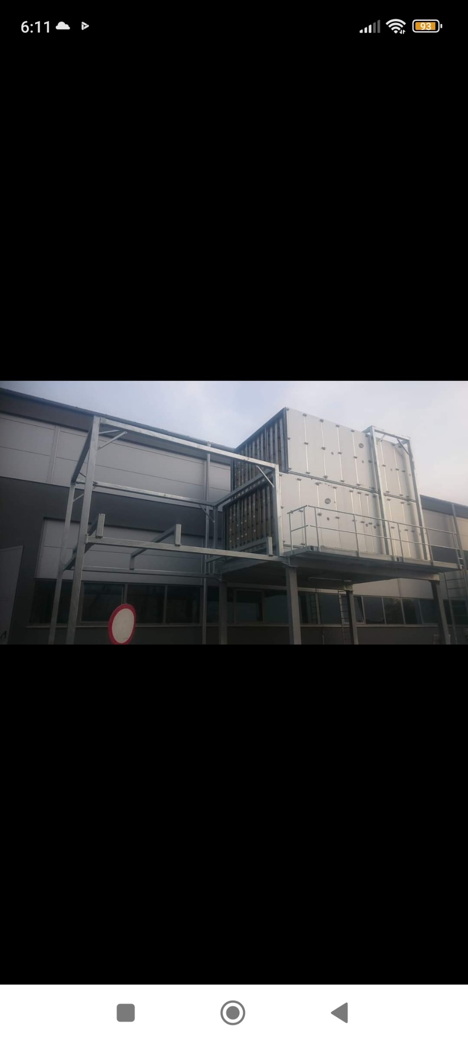 Zewnętrzna instalacja wentylacyjna na dachu budynku przemysłowego, z widocznymi kanałami wentylacyjnymi, metalową konstrukcją wsporczą i platformą dostępową.