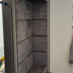 MEBLOTER Paweł Trytek - Wnęka z tapicerowanym siedziskiem i ścianami w odcieniach szarości, zabudowana szafką. Nowoczesny design, minimalistyczny styl, widok z boku, ciemna podłoga.