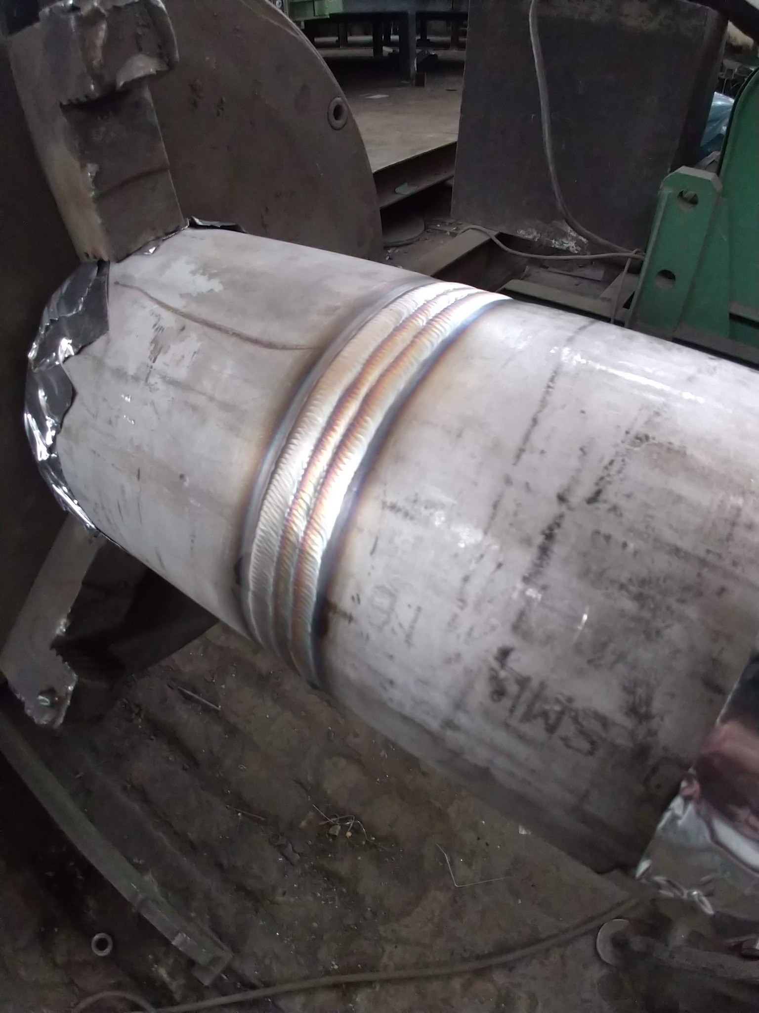 Spawany rurociąg ze stali nierdzewnej, zamocowany w uchwycie obrabiarki, widoczne ślady po spawaniu.