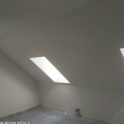 Usługi remontowe Tomasz Stańczyk - Poddasze po malowaniu na biało z dwoma oknami dachowymi, widoczne ślady po pracach wykończeniowych na podłodze.