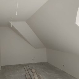 Usługi remontowe Tomasz Stańczyk - Poddasze po szpachlowaniu i malowaniu na biało, widoczne kable wystające z sufitu i listwy przypodłogowe na podłodze.