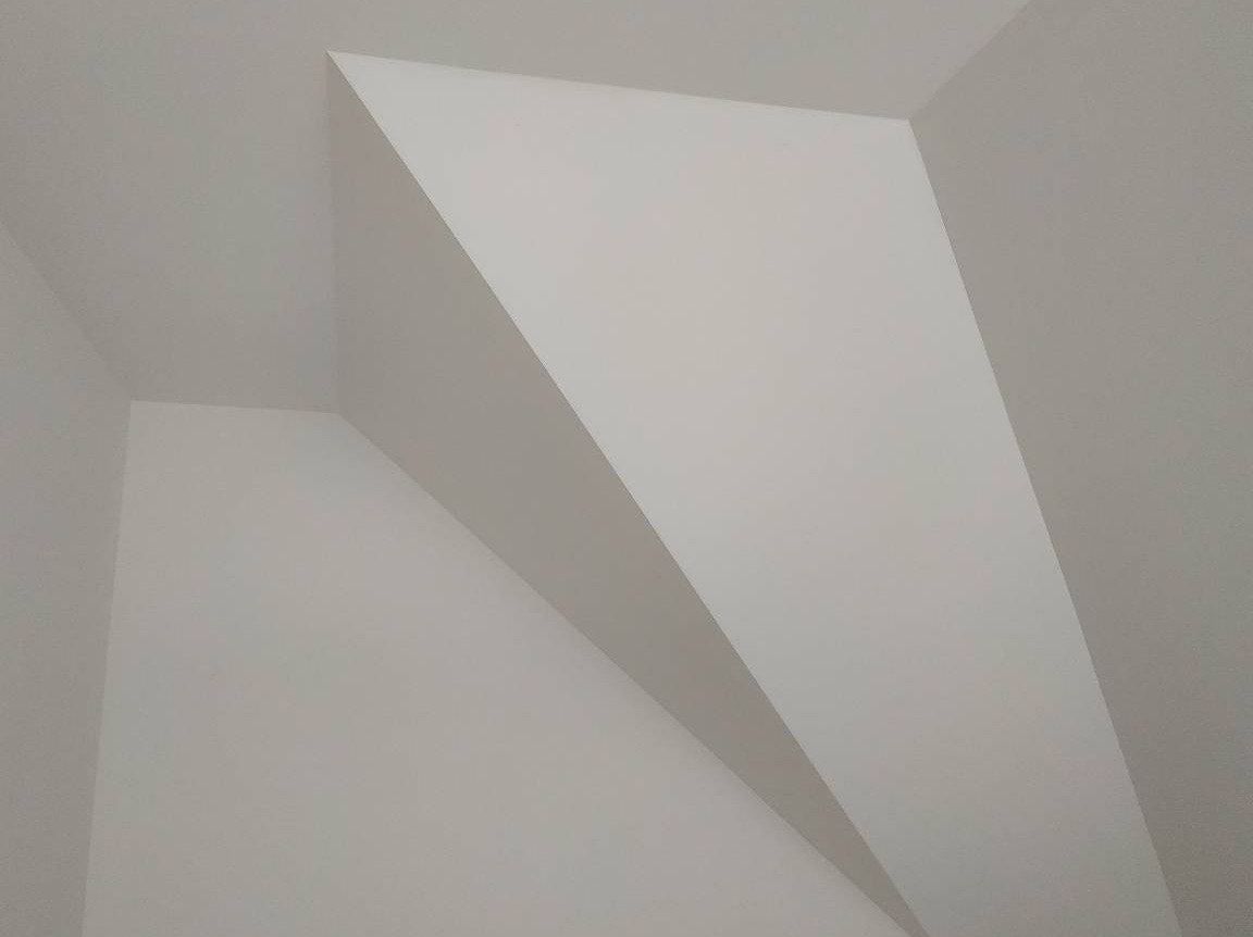 Białe ściany i sufit po malowaniu, widoczne ostre krawędzie i kąty, minimalizm w architekturze wnętrza.