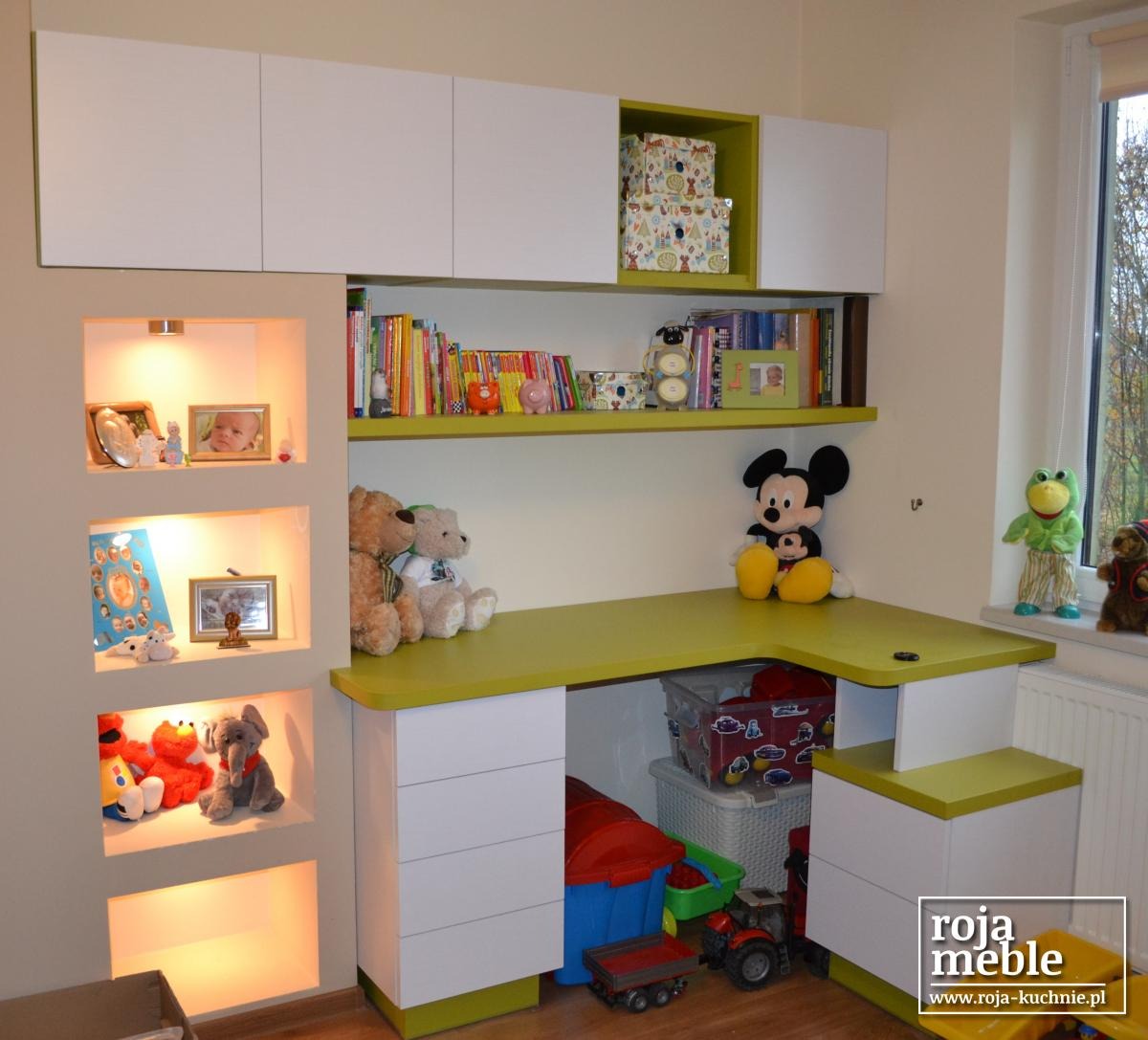 Dziecięcy pokój z biurkiem narożnym i szafkami w kolorze białym i limonkowym, zabawki na biurku i wnękach ściennych, widok na okno.