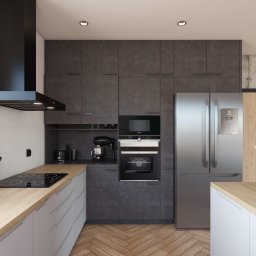Usługi Stolarskie Ireneusz Kołodziejczyk - Nowoczesna kuchnia z szarymi szafkami o teksturze kamienia, drewnianym blatem i podłogą w jodełkę; widoczny sprzęt AGD: lodówka, piekarnik, płyta indukcyjna i czarny okap.