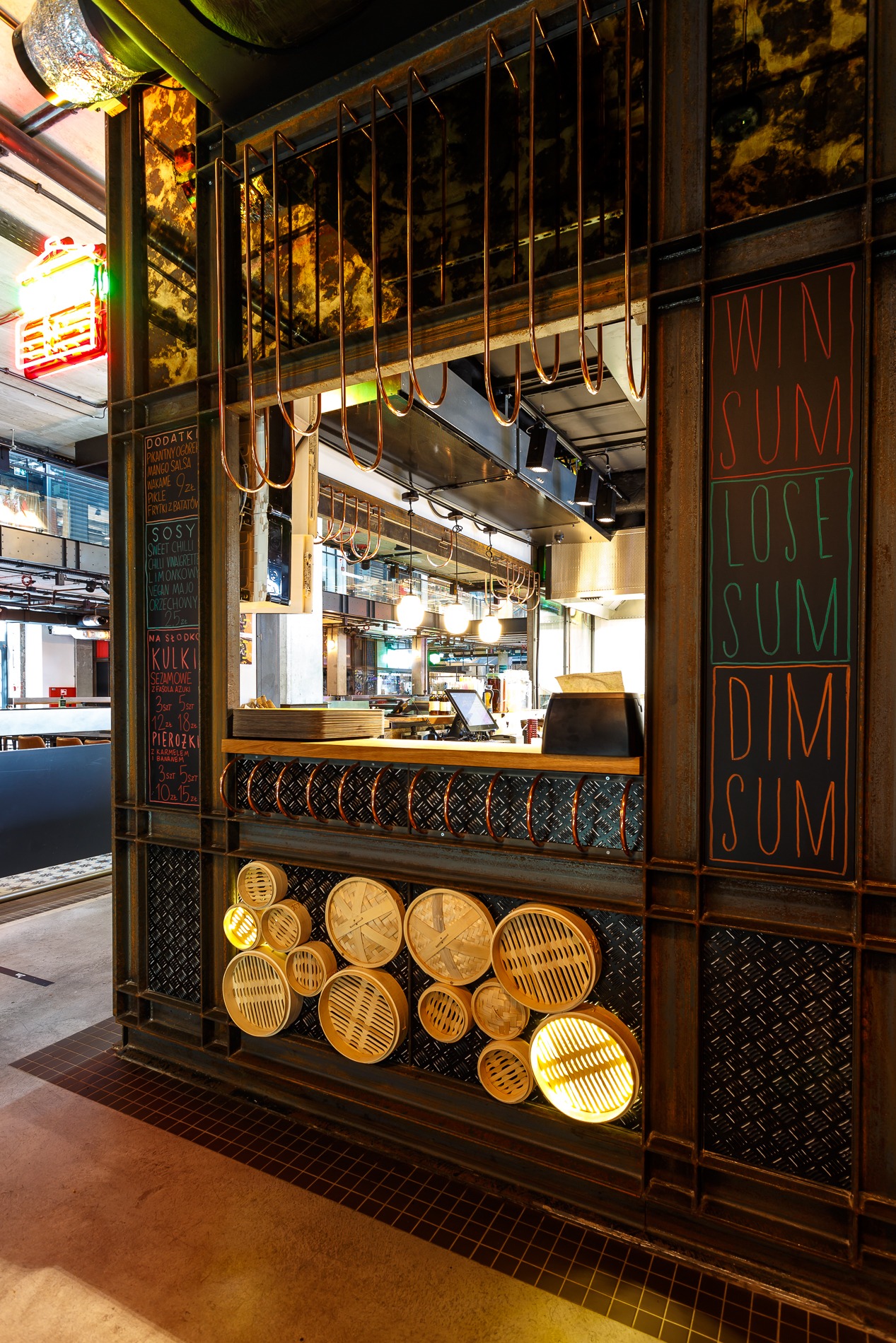 Rustykalny bar z menu wypisanym kredą, dekorowany bambusowymi koszyczkami do dim sum, oświetlonymi od wewnątrz, z widoczną kuchnią w tle.