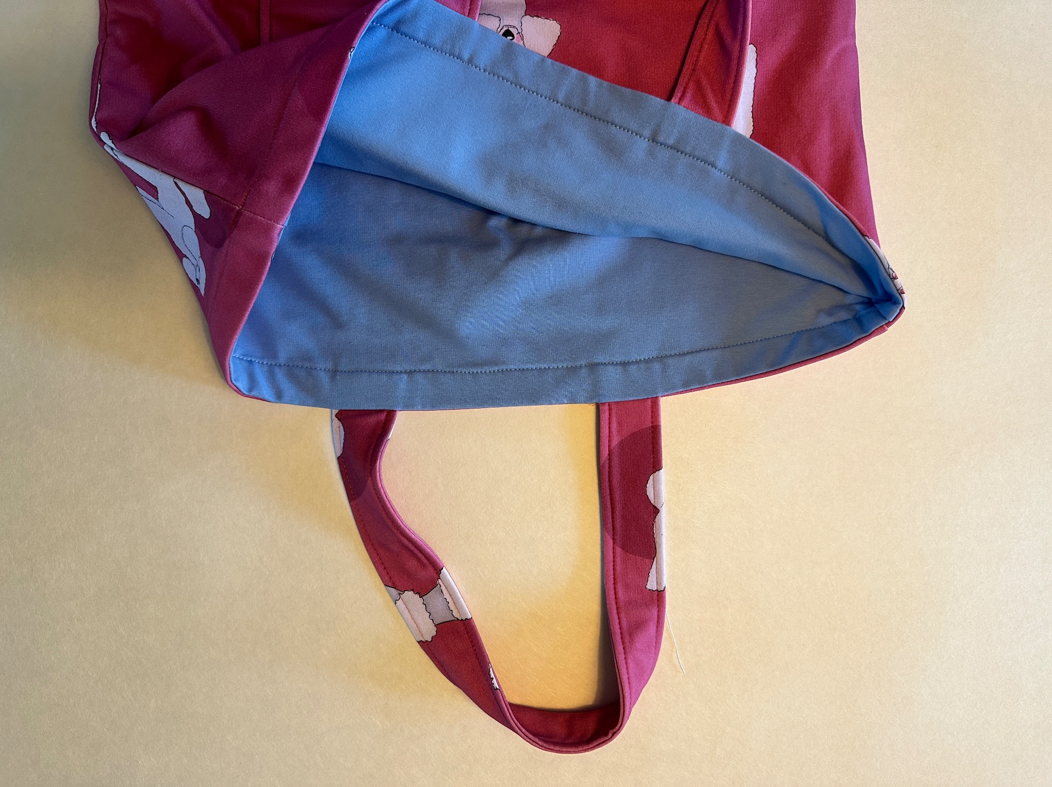 Różowa torba bawełniana z wzorem, z niebieskim wnętrzem, widok od góry na jasnym tle.