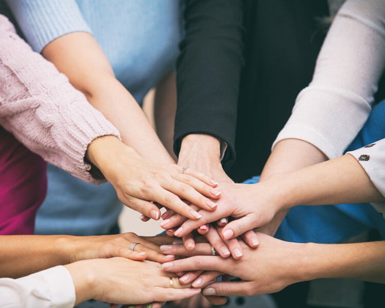 Zespół biura rachunkowego składa dłonie na sobie, symbolizując współpracę i jedność.