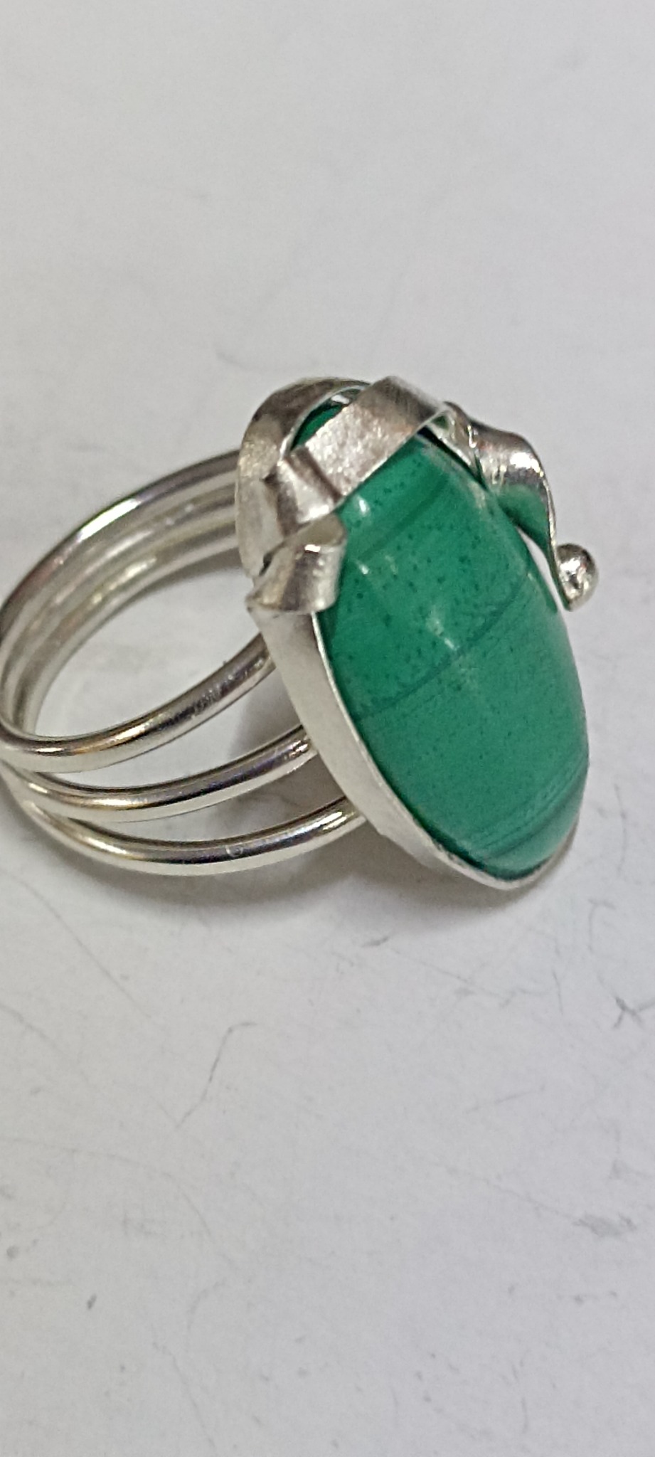 Pierścionek z zielonym kamieniem malachitowym, osadzony w srebrnej, potrójnej obrączce.