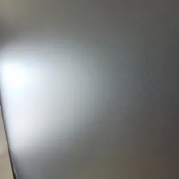 Świeżo pomalowana, gładka ściana w odcieniach szarości z subtelnym gradientem światła, ukazująca delikatną teksturę farby.