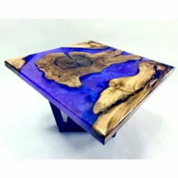 Stolik kawowy z blatem z drewna i żywicy epoksydowej w odcieniach fioletu i brązu, na ciemnej, geometrycznej podstawie.