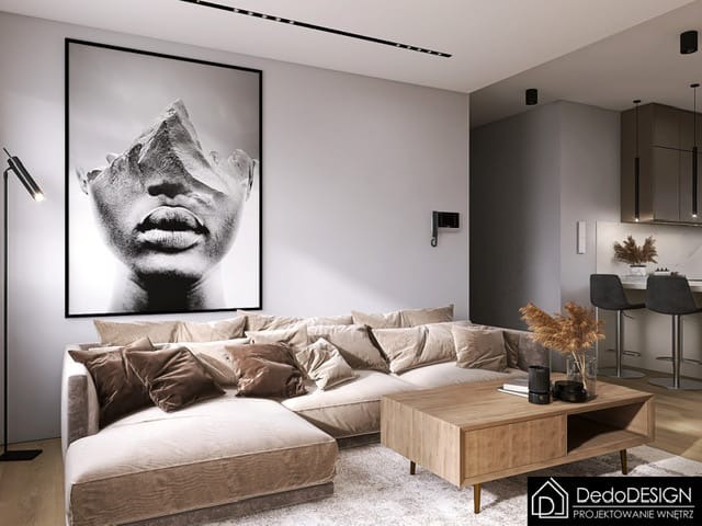 Nowoczesny salon z narożną sofą w odcieniach beżu, drewnianym stolikiem kawowym i dużym, czarno-białym abstrakcyjnym portretem na ścianie. Minimalistyczna lampa podłogowa obok sofy. Aneks kuchenny...