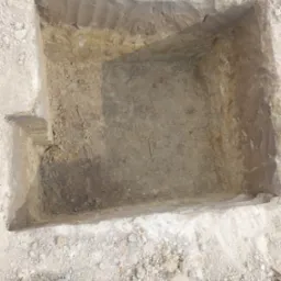 Wykopany fundament pod budynek z widoczną stopą fundamentową, ziemia piaszczysta.