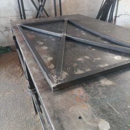 CraftsMan - Stalowa konstrukcja kratowa, spawana na stole warsztatowym, widoczne spawy i niedoskonałości obróbki metalu.