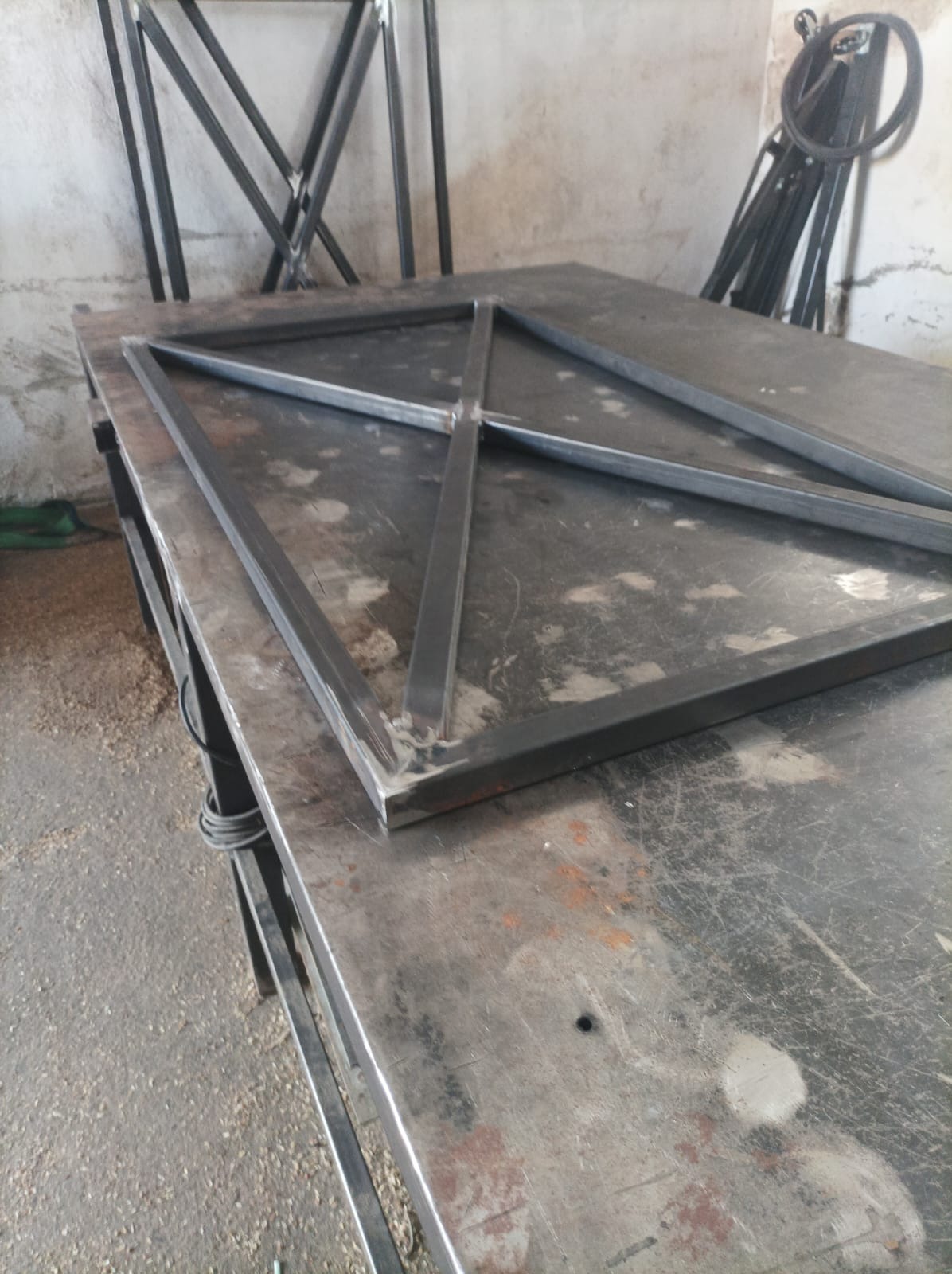 Stalowa konstrukcja kratowa, spawana na stole warsztatowym, widoczne spawy i niedoskonałości obróbki metalu.