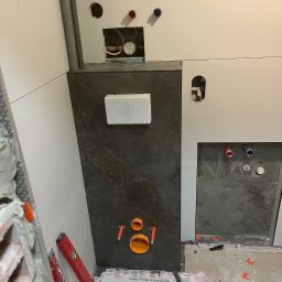 AR-DECOR WYKOŃCZENIA WNĘTRZ ARKADIUSZ PARZYGNAT - Montaż stelaża podtynkowego WC z częściowo ułożonymi płytkami w łazience. Widoczne poziomice i elementy instalacji wodno-kanalizacyjnej.