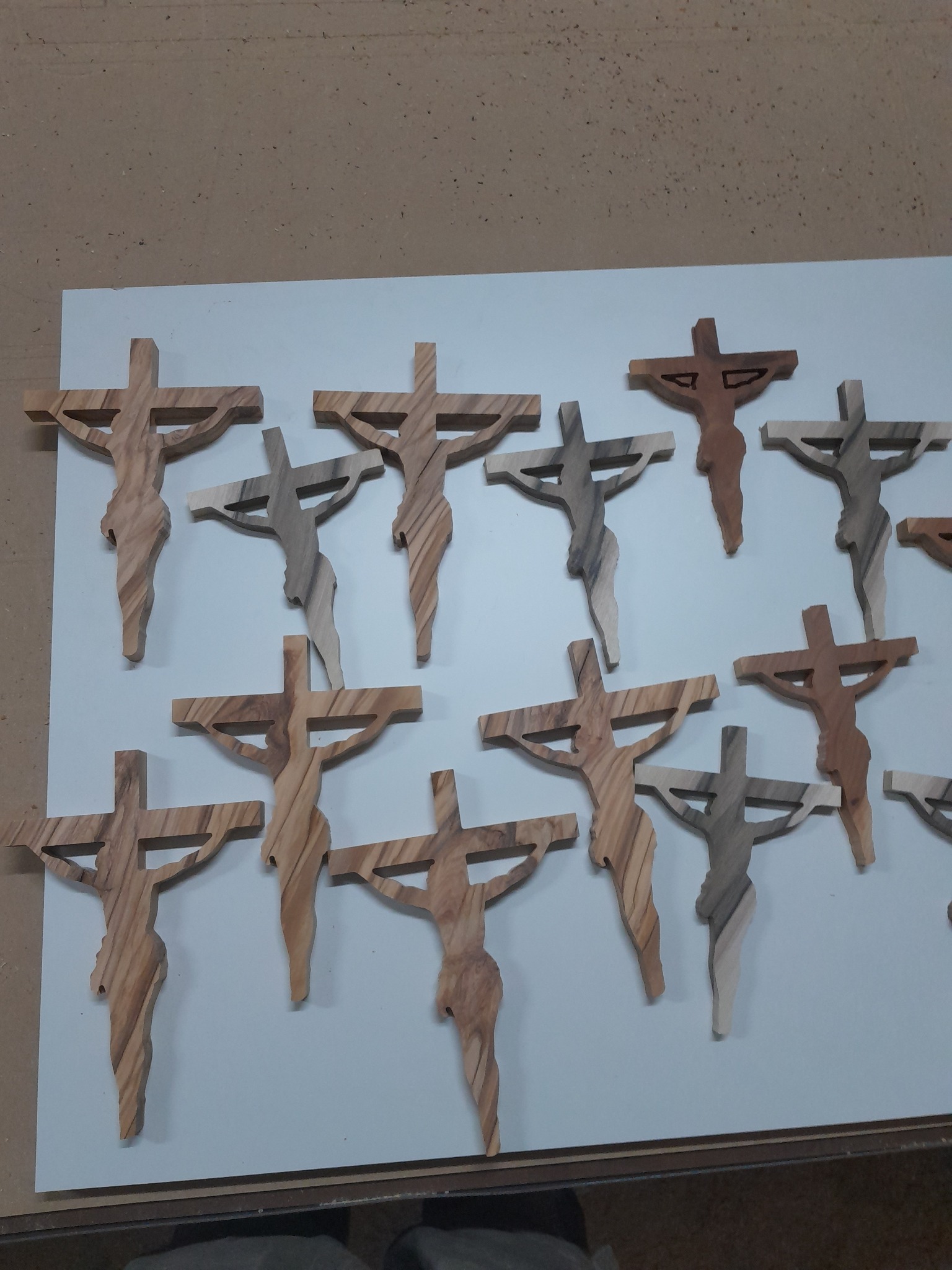 Drewniane krucyfiksy z widocznym usłojeniem, ułożone na białym podłożu. Realizacja z miejscowości Skierniewice.