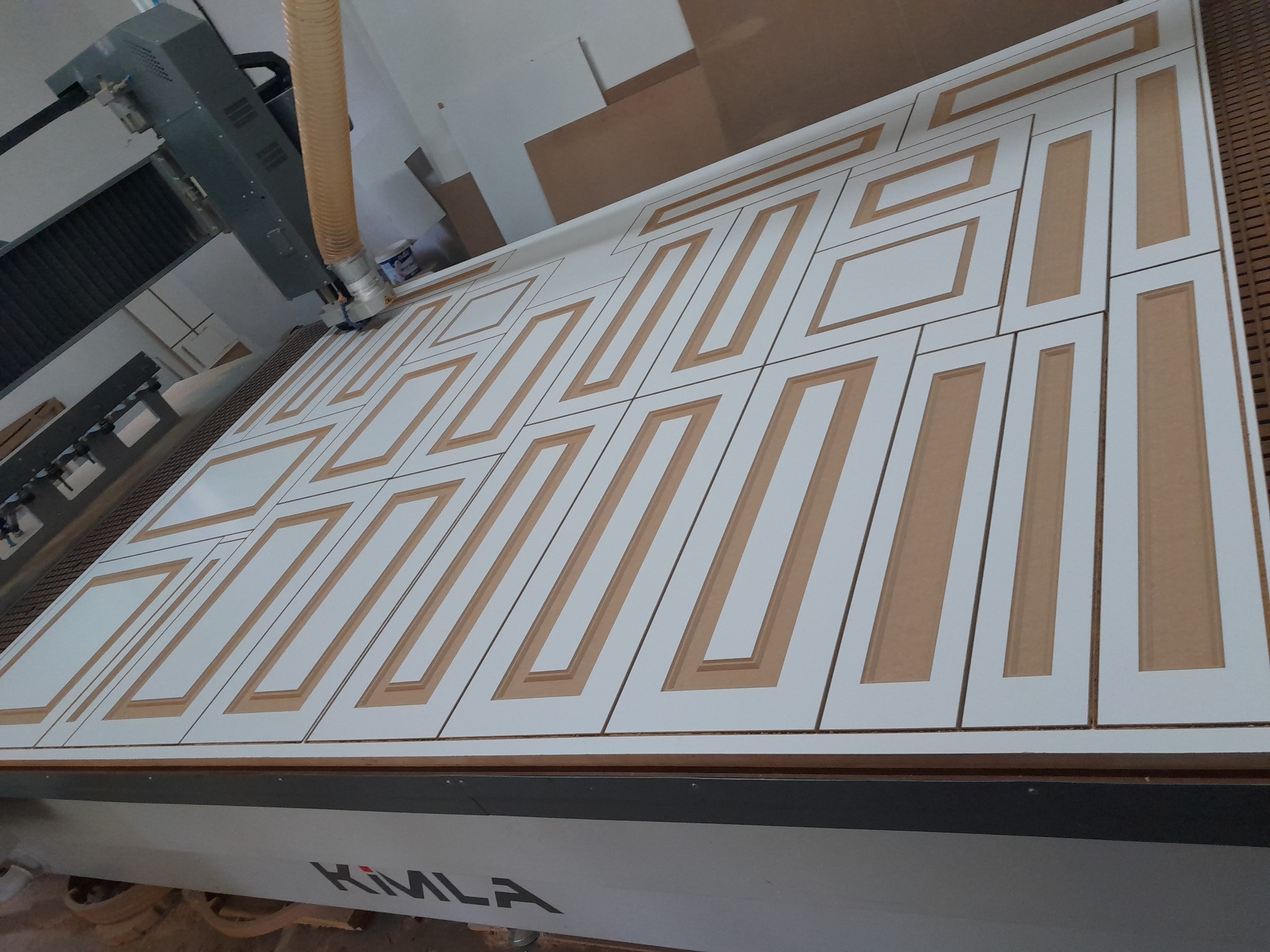 Frezarka CNC w trakcie wycinania wzoru z płyty MDF, widoczny odciąg pyłu i logo maszyny KIMLA.