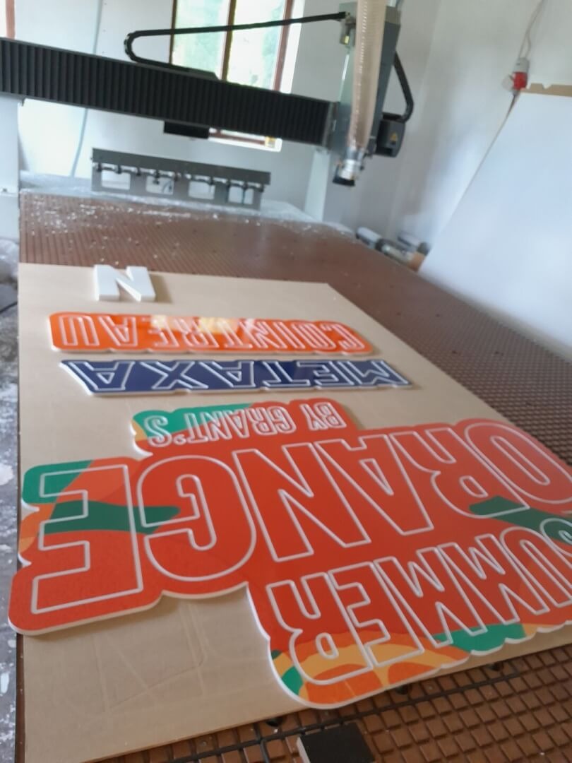 Wycinanie reklamowych napisów z pianki na ploterze CNC: 'Summer Orange by Grant's', 'Metaxa', 'Cointreau' i litera 'N'.