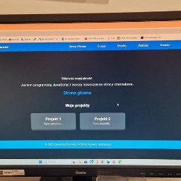 Dawid Grochowski - Monitor iiyama z otwartą stroną internetową 'Dawid Grochowski', prezentującą portfolio programisty JavaScript z sekcjami: Strona Główna, O mnie, Projekty, Portfolio, Kontakt.