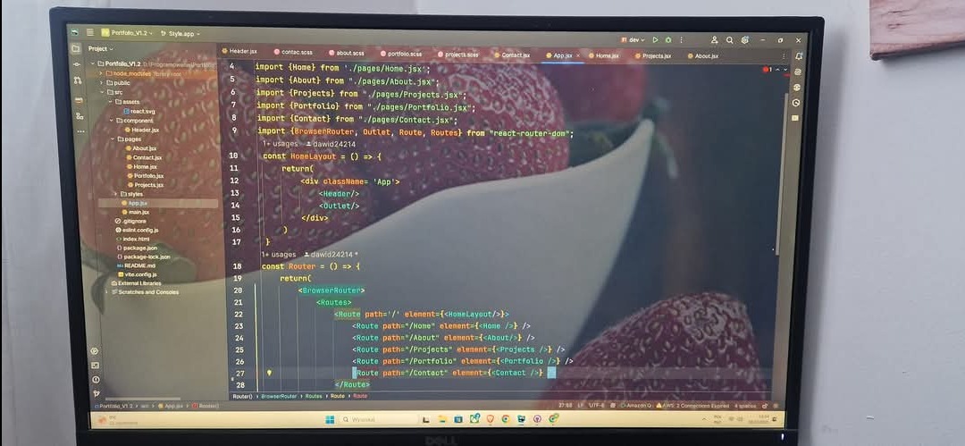 Ekran monitora Dell z kodem React i motywem truskawkowym w tle. Widoczny edytor kodu z otwartymi plikami .jsx. Programowanie stron WWW w praktyce.