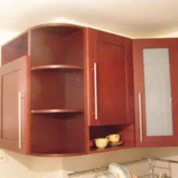 Ciemnobrązowa, narożna szafka kuchenna na wymiar z półkami i przeszklonym frontem, widoczne filiżanki na półce, oświetlenie sufitowe.