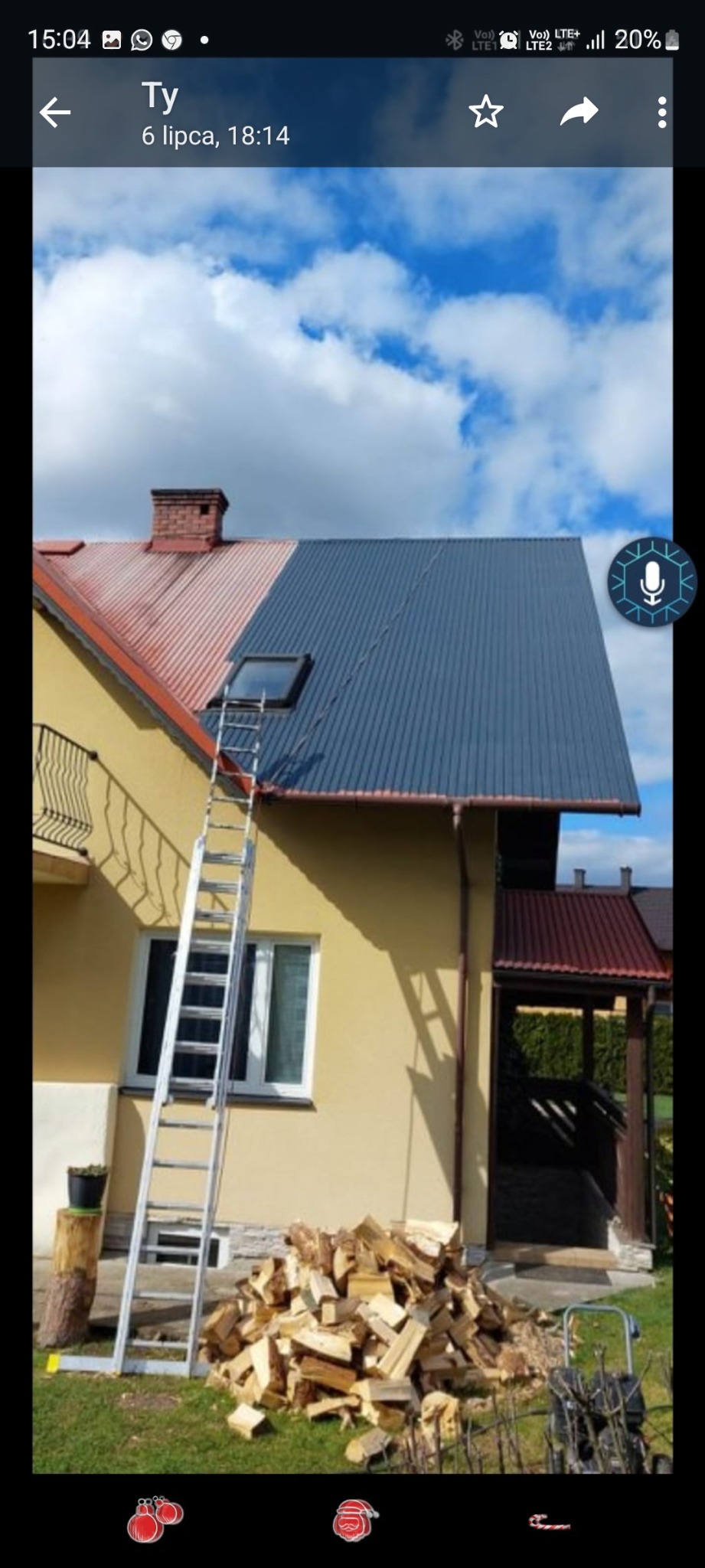 Dwukolorowy dach z blachy trapezowej, część pomalowana na szaro, część w kolorze ceglastym, drabina oparta o dach, fragment elewacji domu w kolorze żółtym, sterta drewna na trawniku.