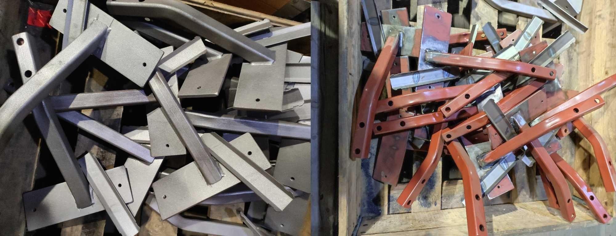 Stalowe elementy konstrukcyjne: po lewej szare po obróbce, po prawej pomalowane na czerwono, ułożone w drewnianej skrzyni.