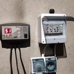 SYSTEMUS SP. Z O. O. - Panel sterowania temperaturą ST-21 z wyświetlaną wartością 51 stopni Celsjusza, obok skrzynka elektryczna Zamel PCU-510 i gniazda wtykowe z przezroczystymi osłonami, zamontowane na szarej...