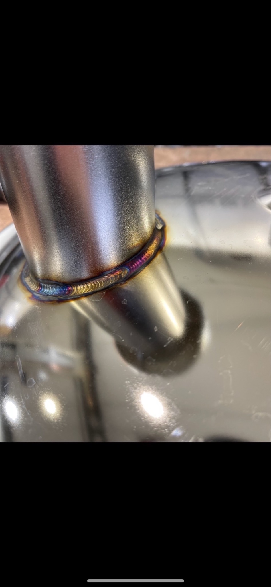 Połączenie spawane rury ze stali nierdzewnej, widoczne tęczowe przebarwienia na spoinie, wskazujące na wysoką jakość wykonania.