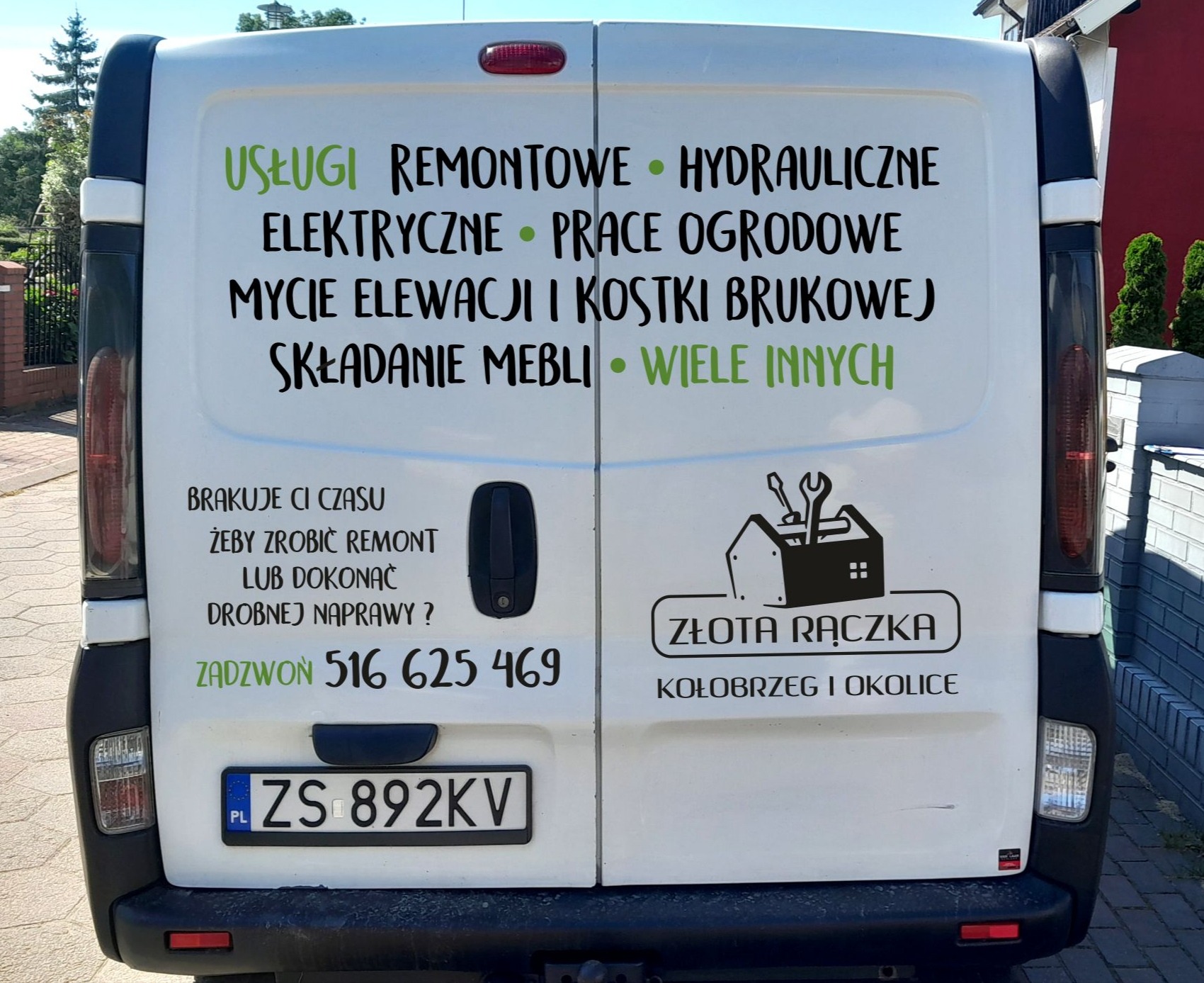 Tył białego samochodu dostawczego z reklamą usług remontowych, hydraulicznych, elektrycznych, ogrodowych, mycia elewacji i kostki brukowej, składania mebli oraz logo 'Złota Rączka Kołobrzeg...