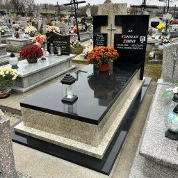 TOMBET NATALIA DOBIES - Czarny, polerowany nagrobek z jasnego granitu na cmentarzu, z pomarańczowymi chryzantemami w doniczce i lampionem na płycie.