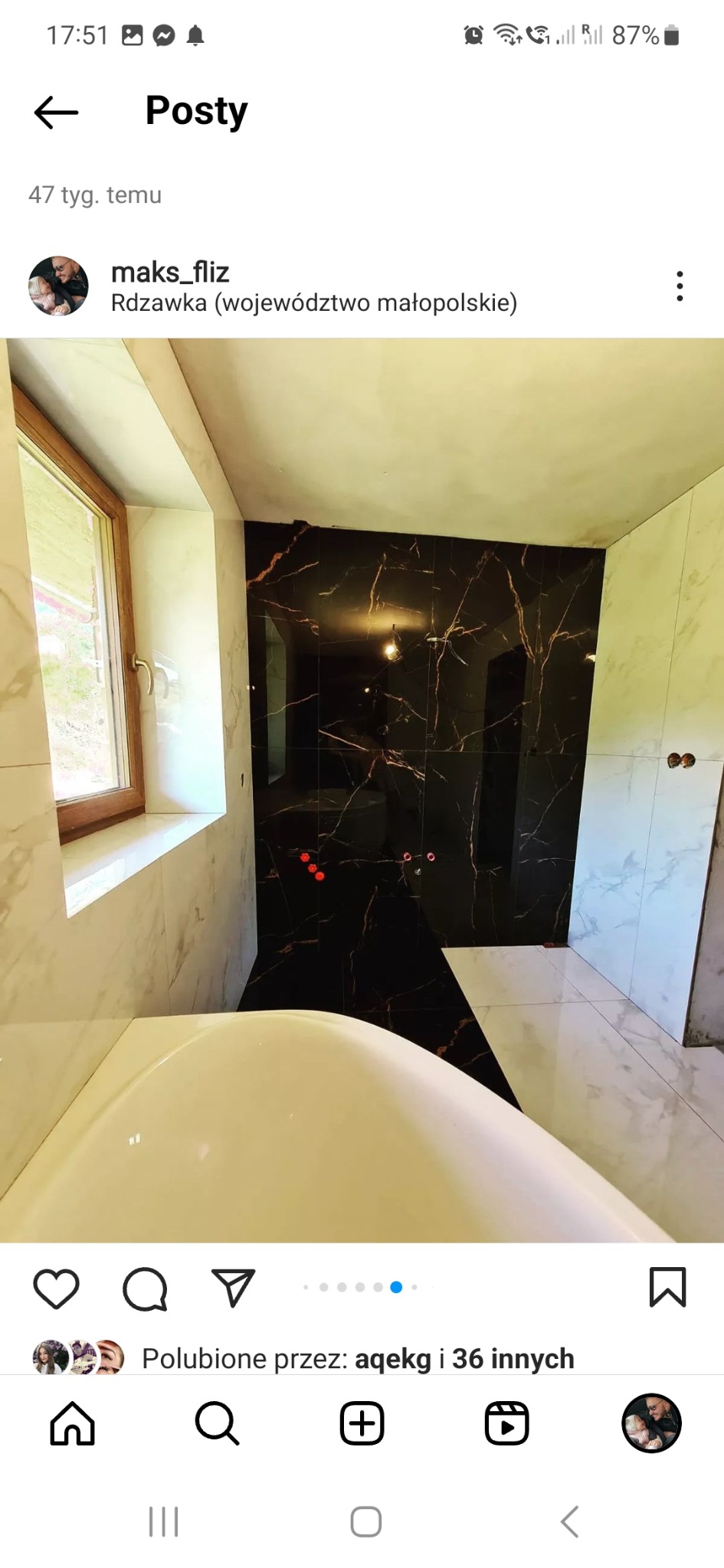 Łazienka w trakcie wykańczania: widoczna wanna, ściany wyłożone białymi i czarnymi płytkami z marmurkowym wzorem, okno z drewnianą ramą.