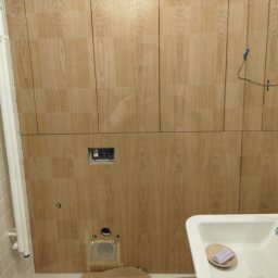 WALE Spółką z ograniczoną odpowiedzialnością - Montaż jasnych paneli ściennych z usłojeniem drewna w łazience w Przeźmierowie, z przygotowanymi przyłączami pod toaletę, instalacją elektryczną i otworem wentylacyjnym.