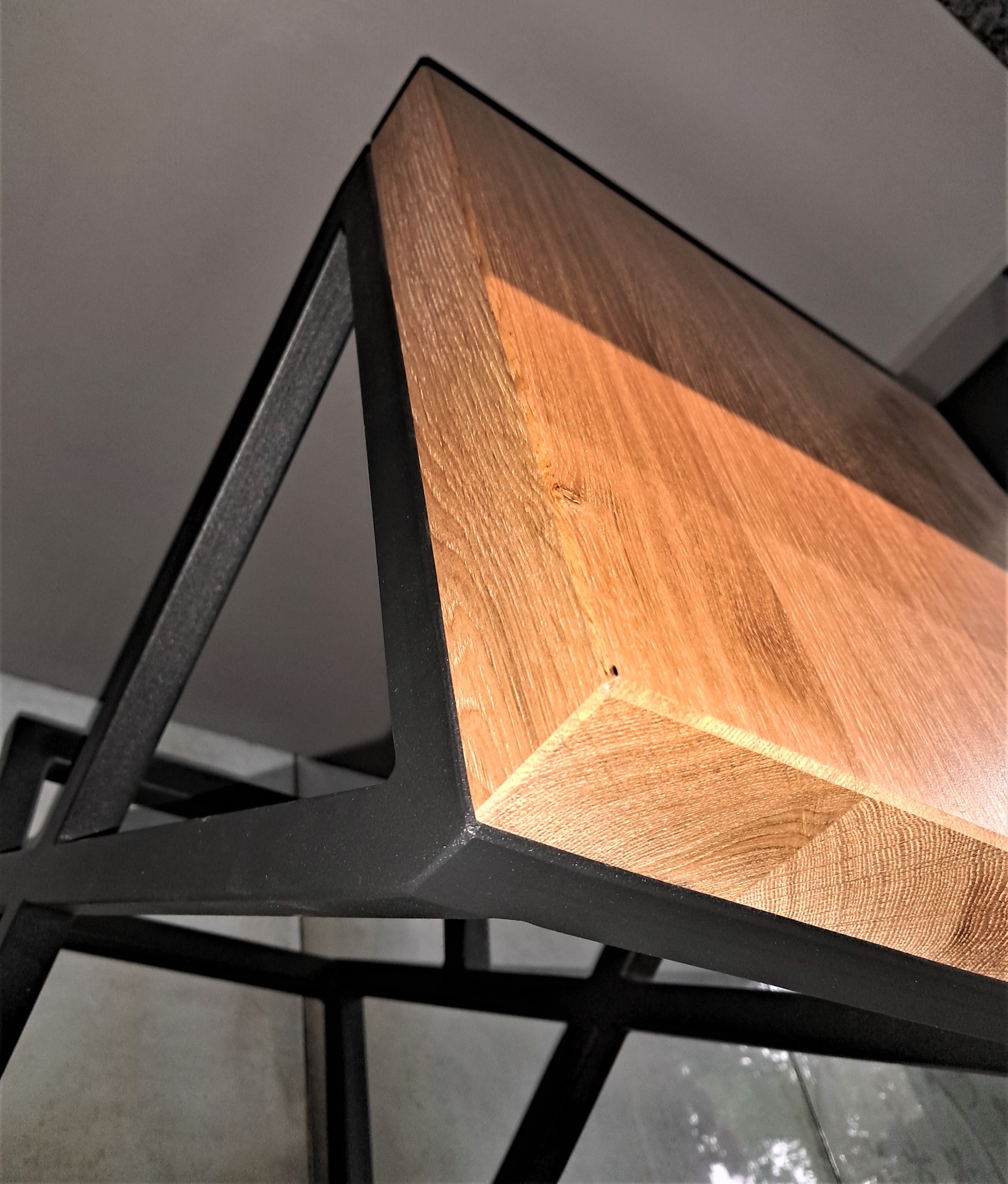 Blat z jasnego drewna dębowego, osadzony na czarnej, metalowej konstrukcji w stylu industrialnym, widok z dołu pod kątem.