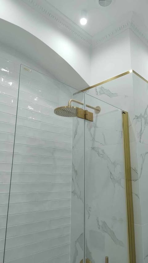 Kabina prysznicowa z deszczownicą w odcieniach bieli i złota, wykończona płytkami imitującymi marmur, zrealizowana w Tarnowskich Górach.