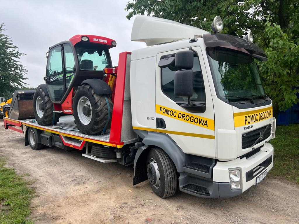 Laweta Volvo 'Pomoc Drogowa' przewozi czerwony podnośnik teleskopowy Manitou na platformie z czerwonymi zabezpieczeniami.