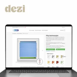 Laptop wyświetlający stronę internetową z ofertą rolet plisowanych bezinwazyjnych w kolorze błękitnym, widok na okno z zamontowaną roletą i opcje wyboru tkanin.